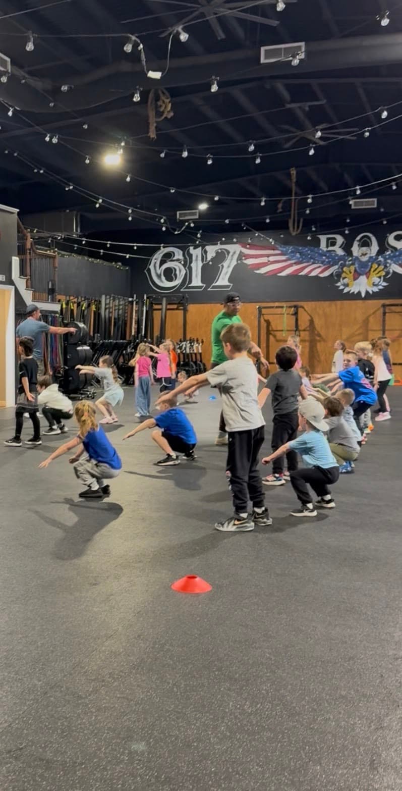 Kids in a squat line with a coach